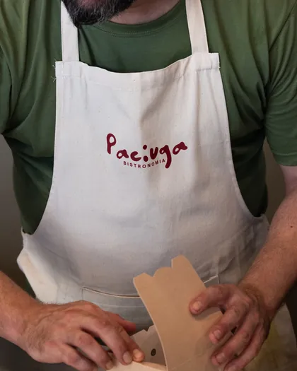 Mani che chiudono una scatola da asporto, grembiule con il logo Paciuga