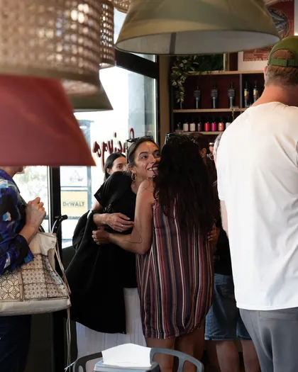 Il locale pieno di gente: due amiche si abbracciano vicino all'ingresso